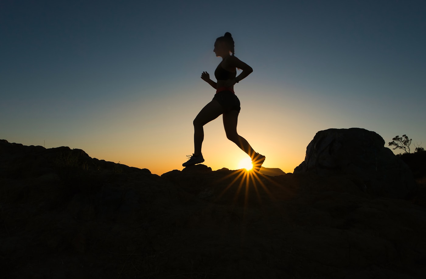Runner on a ridge at sunrise with live heart-rate and training load overlays